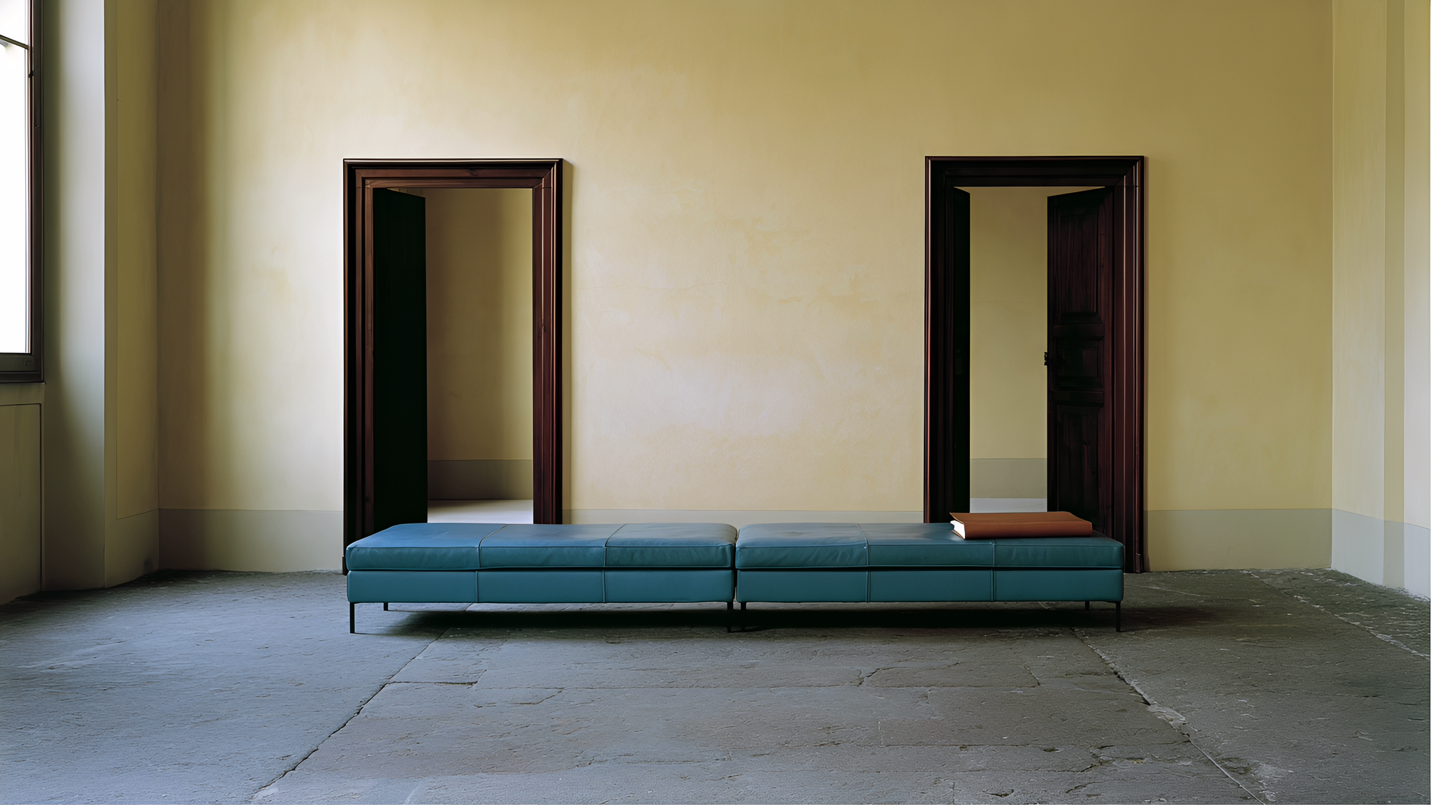 A blue-green leather settee and a closed folio in an ochre historic salon